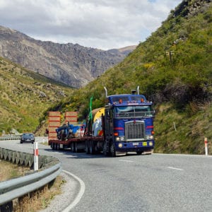 Large blue truck driving between two mountains