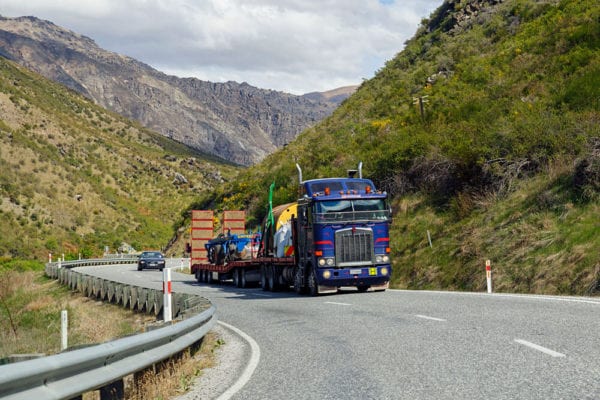 Large blue truck driving between two mountains